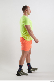 Joel  1 dressed green sneakers orange shorts side view…